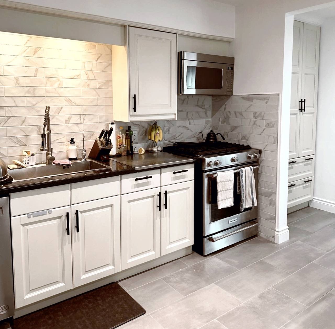 After photo of the same kitchen with newly painted off-white (Mist Air by Benjamin Moore) cabinets and pantry doors, featuring new gold hardware and a brighter, more open feel ~ George town, Toronto.