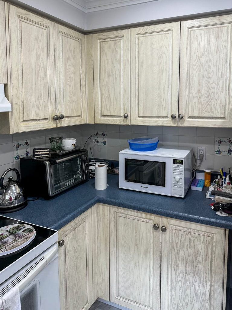 Worn, stained white oak kitchen cabinet doors showing visible wear, tear, and discolouration in a Toronto condo kitchen before painting.