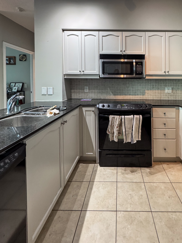 Refinished kitchen cabinet doors in a Toronto condo, painted a soft off-white with a hint of gray (Benjamin Moore's Pale Oak). The finish is smooth, modern, and bright.