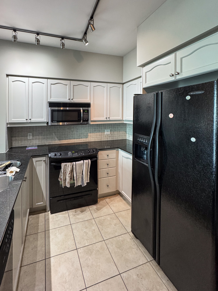 Refinished kitchen cabinet doors in a Toronto condo, painted a soft off-white with a hint of gray (Benjamin Moore's Pale Oak). The finish is smooth, modern, and bright.